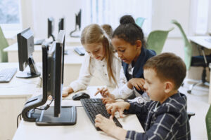 Tres jóvenes de diferentes etnias trabajan en un ordenador para adquirir competencias digitales, clave para fomentar el acceso a la universidad.